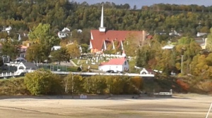 The oldest wooden chapel in North America, with the newer church just above. They share the cemetary.
